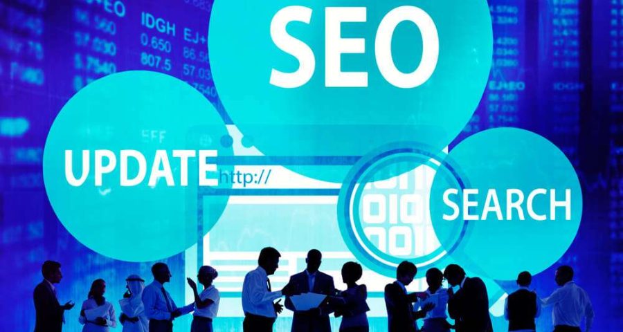 Business people standing in front of computer screen with SEO, Update, & Search Bubbles in the background