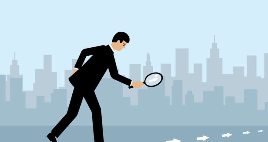 man with magnifying glass following arrows