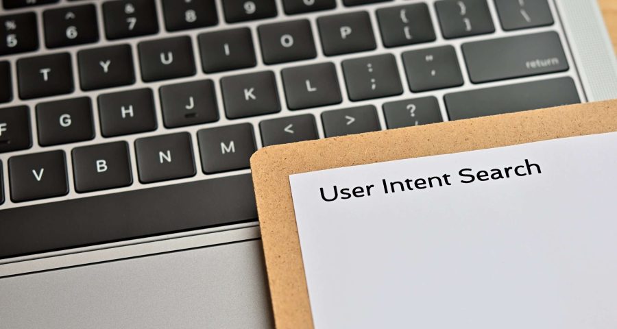 laptop with paper in front reading user intent search