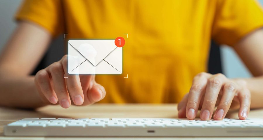 email graphic hovering above a keyboard with person typing