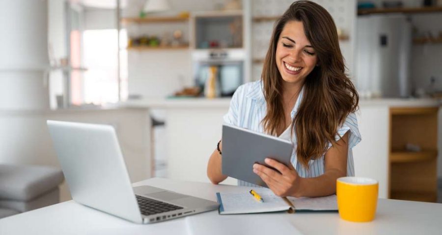 woman on laptop and ipad smiling