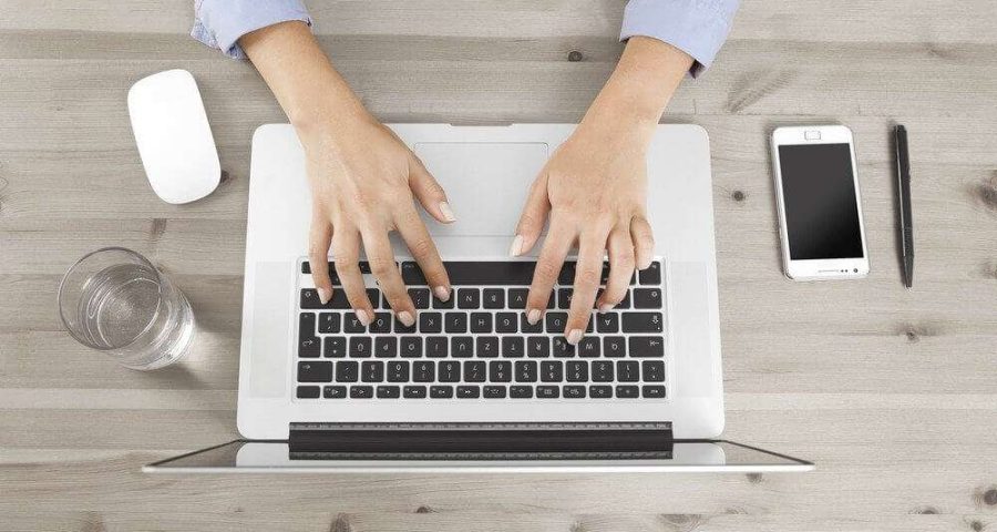 Woman typing on laptop keyword at desk